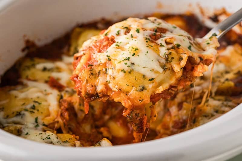 lazy lasagna being served out of slow cooker with a metal spoon.