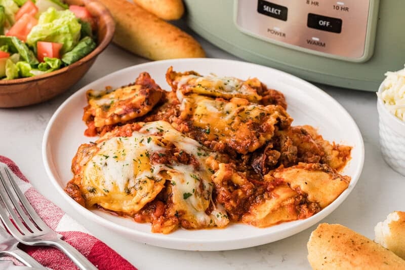 serving the slow cooker ravioli lasagna on a white plate.