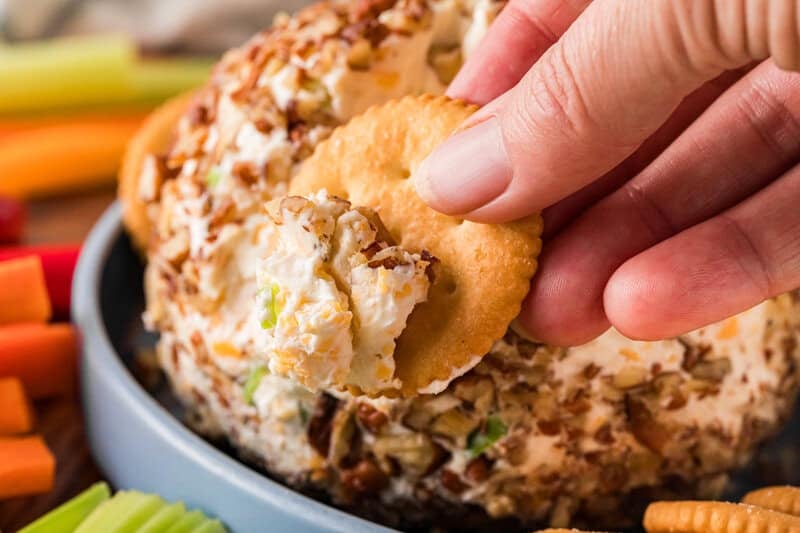 closeup of a cracker with the Cheese Ball on it in hand.