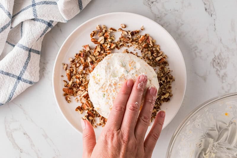 rolling the cheese ball in the nuts.